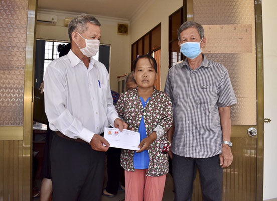 Ông Nguyễn Hữu Đức, Phó Chủ tịch Hội Nạn nhân chất độc da cam và Bảo trợ xã hội tỉnh (bìa trái) trao tiền hỗ trợ cho bệnh nhân nghèo.