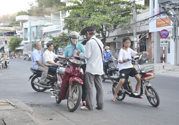 Hồn nhiên dừng xe máy giữa đường Trần Phú, Phường 5 để mua vé số.