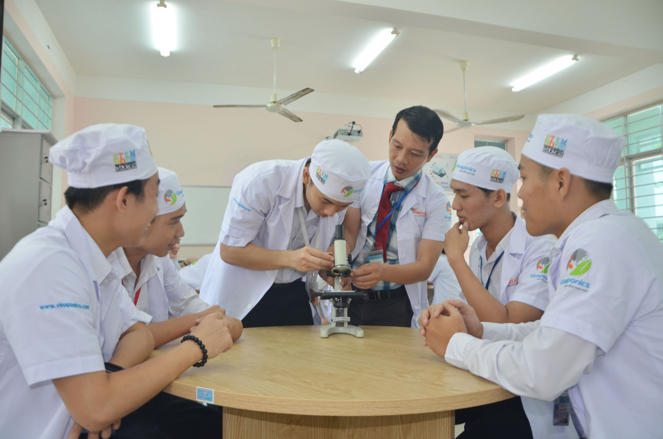 Thầy Trần Song Hào (đứng) hướng dẫn các thành viên CLB Stem thực hành quan sát tiêu bản kính hiển vi.