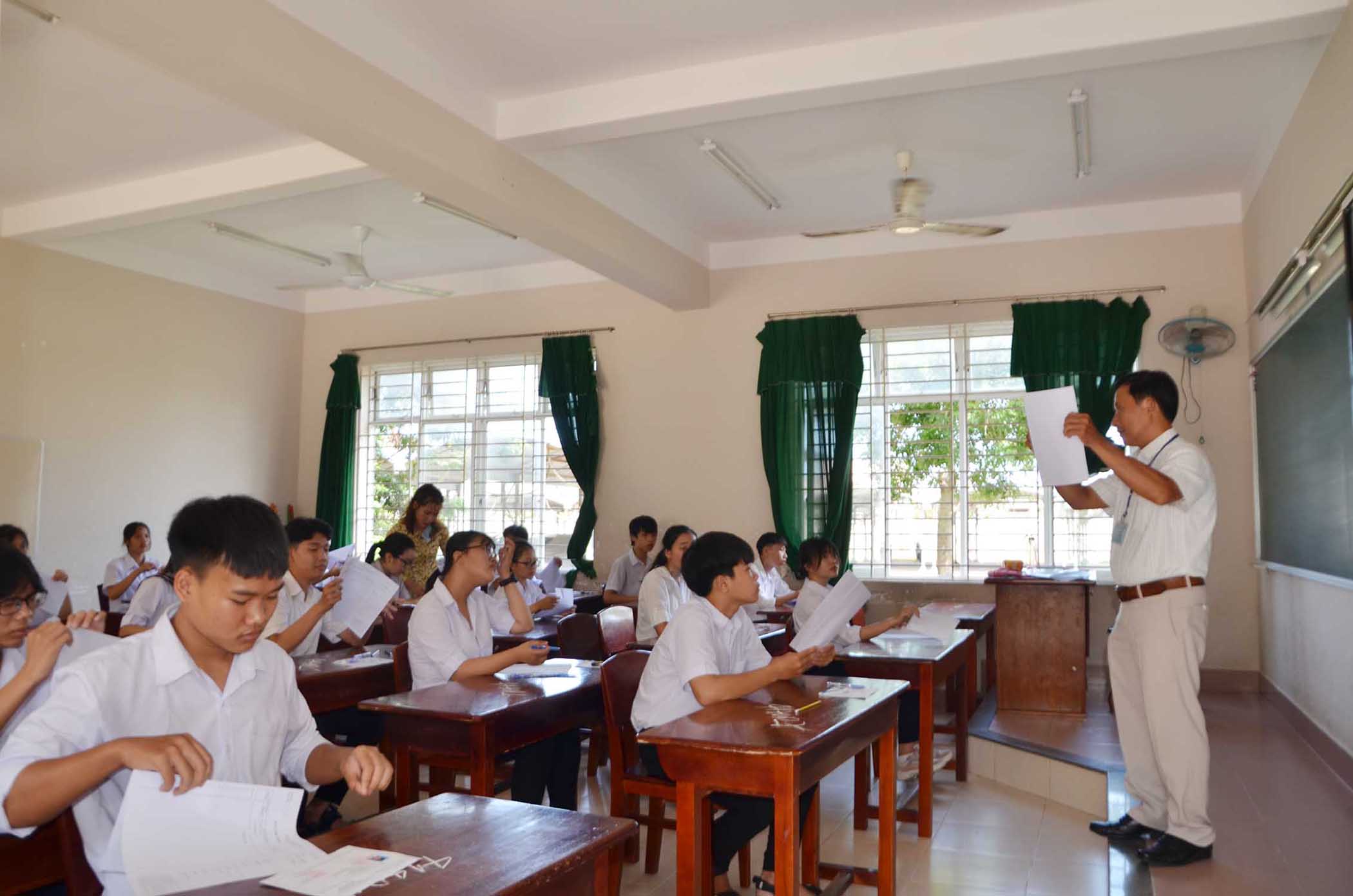 Giám thị tại điểm Trường THPT Minh Đạm, huyện Long Điền hướng dẫn thí sinh cách viết giấy thi. Ảnh: DIỄM QUỲNH