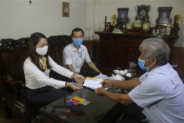 Cán bộ BHXH thực hiện chi trả lương hưu tại nhà cho người lao động