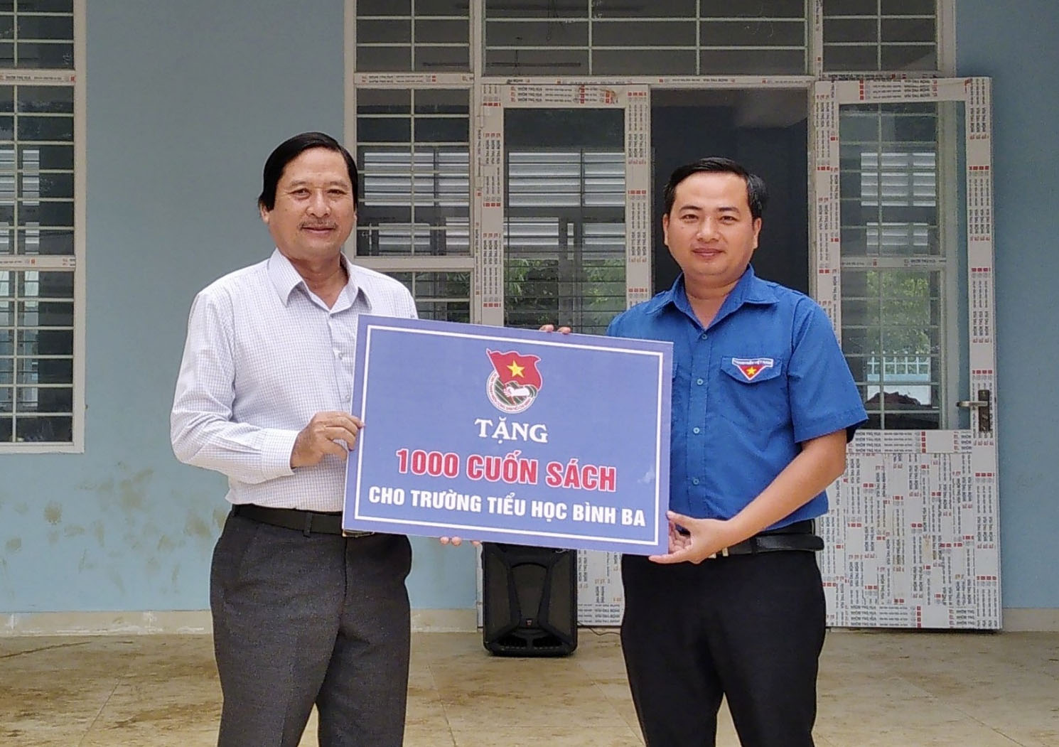 Anh Nguyễn Trung Minh, Bí thư Huyện Đoàn Châu Đức  trao bảng tượng trưng 1.000 cuốn sách cho thầy Nguyễn Khương, Hiệu trưởng trường TH Bình Ba.
