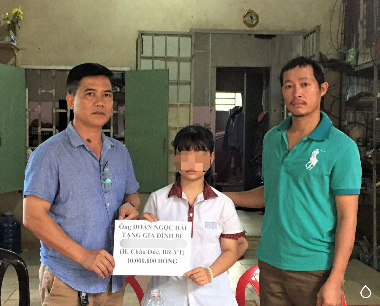 Đại diện phóng viên địa phương (bìa trái) trao 10 triệu đồng của ông Đoàn Ngọc Hải tới bé M. và gia đình. 