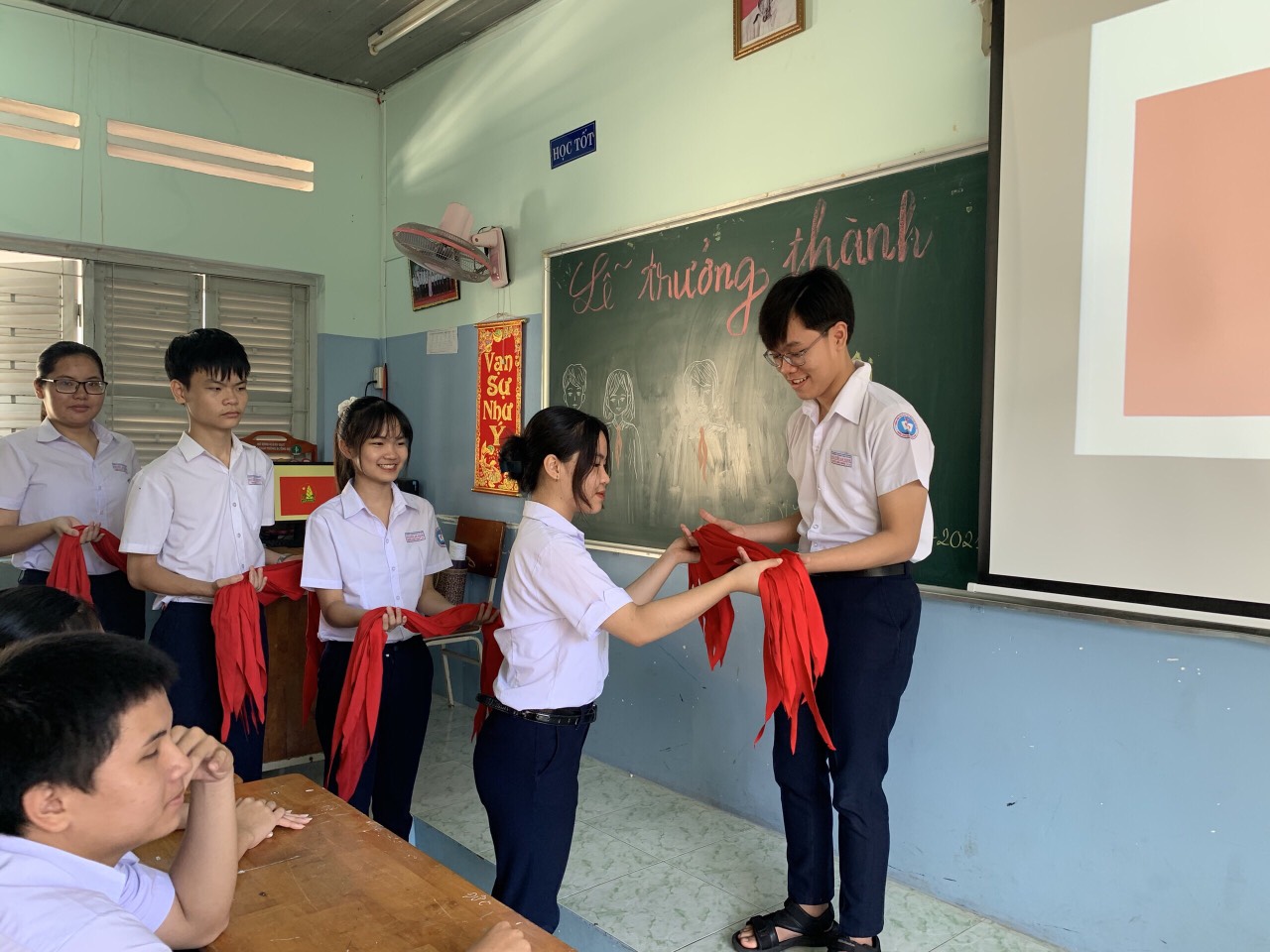 Các em HS lớp 9/9, trường THCS Nguyễn An Ninh trao lại chiếc khăn quàng đỏ trong Lễ trưởng thành Đội.