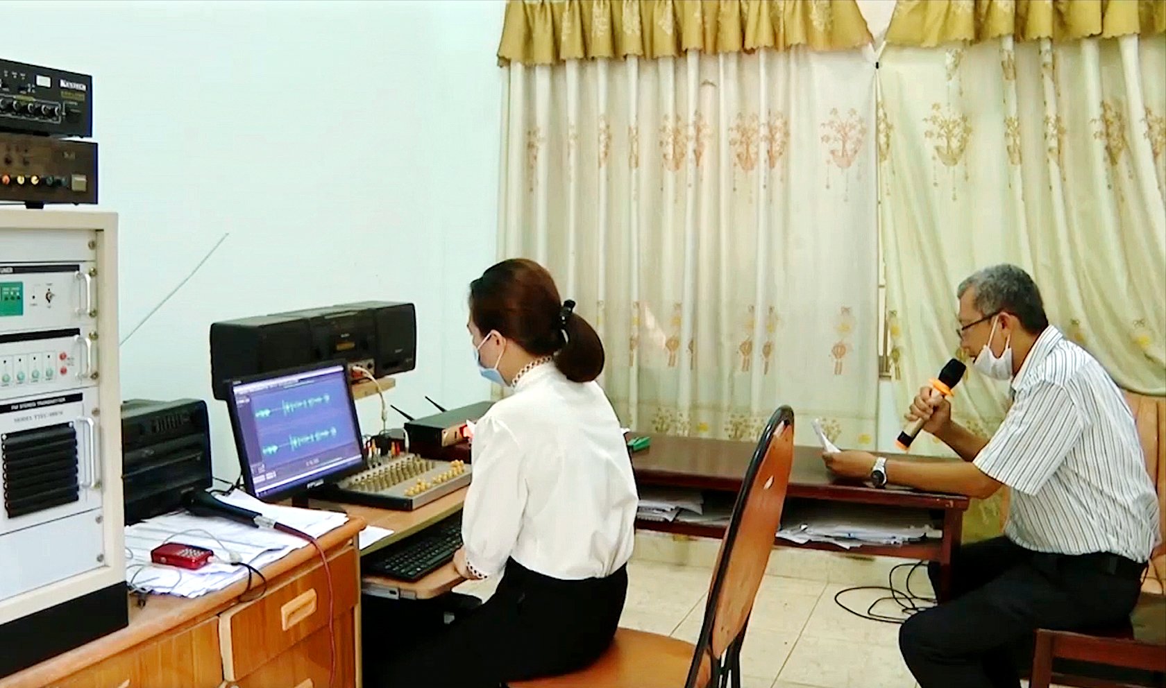 Ông Nguyễn Xuân Tường, Công chức Văn hóa-Xã hội UBND xã Hòa Long đang đọc các thông báo, thu âm chuẩn bị bản tin trưa phát trên loa truyền thanh của xã.