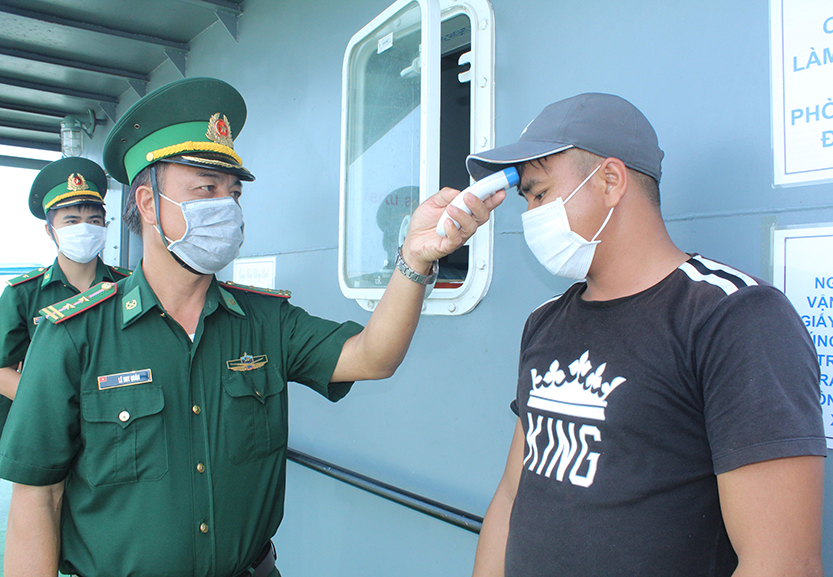 Cán bộ, chiến sĩ Đồn Biên phòng Bến Đá kiểm tra thân nhiệt thuyền viên tàu đánh bắt hải sản cập bến khu vực cửa sông Bến Đình.