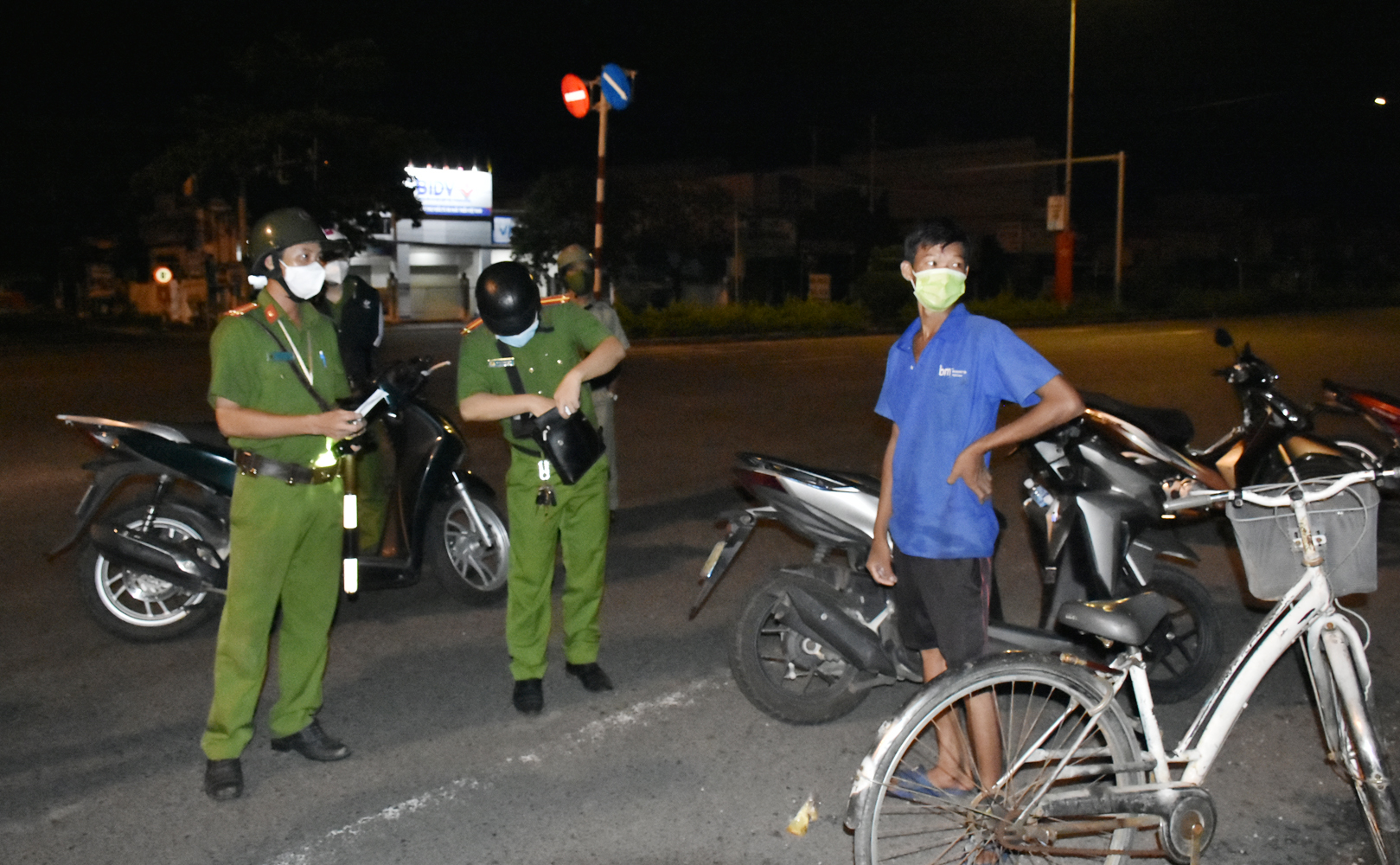 Bất cứ người nào ra đường ban đêm đều được dừng lại kiểm tra. Trong ảnh: Tổ tuần tra kiểm tra một người đi xe đạp qua ngã tư Cái Mép (phường Tân Phước).