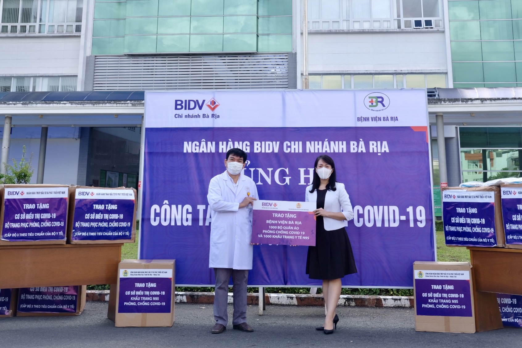 Bà Nguyễn Thanh Thủy, Giám đốc BIDV, Chi nhánh Bà Rịa trao bảng tượng trưng tặng quần áo bảo hộ và khẩu trang cho đại diện Bệnh viện Bà Rịa. Ảnh: THU THẢO