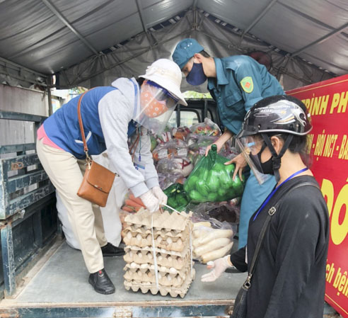 Bà Trần Thị Thu Hương, Chủ tịch Hội LHPN phường 11 (trái) vận chuyển nhu yếu phẩm để tặng cho người dân địa phương bị ảnh hưởng bởi dịch COVID-19.