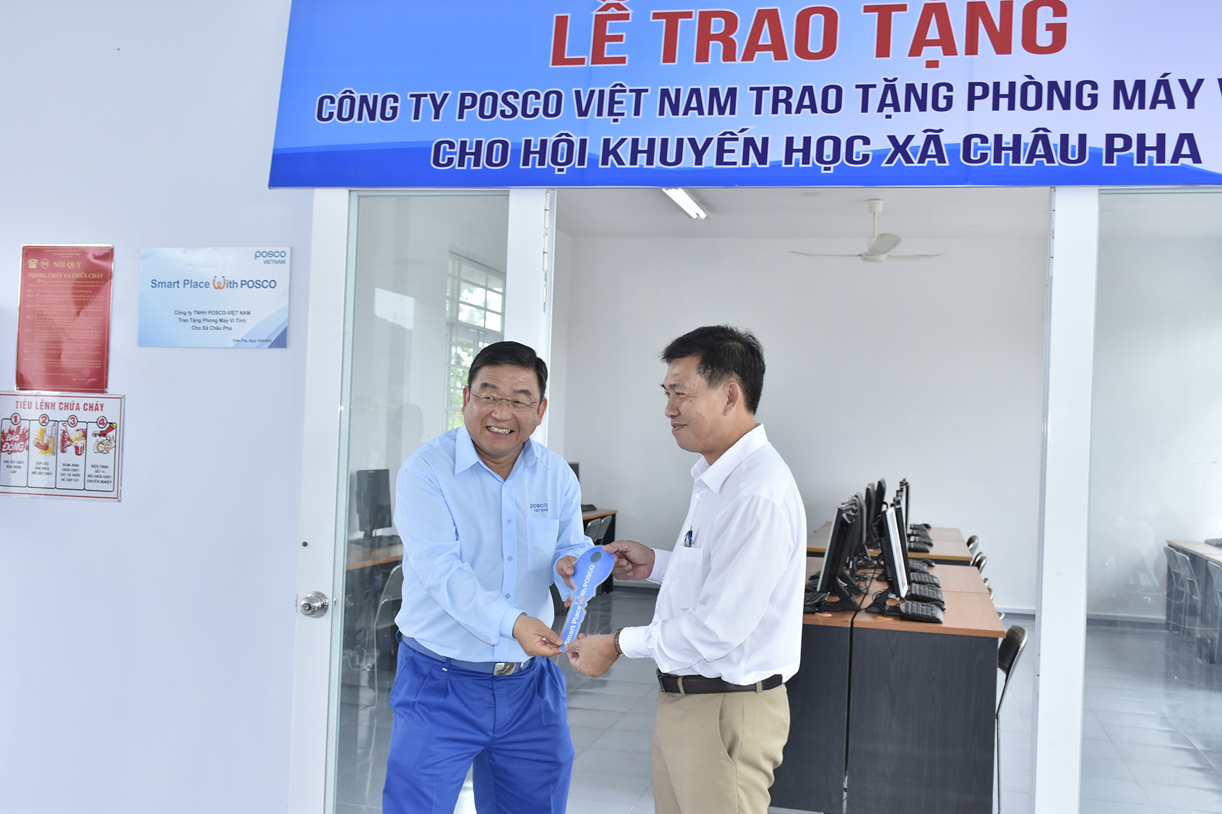 Ông Yoon Chang Woo, Tổng Giám đốc Công ty TNHH Posco Việt Nam (bên trái) trao chìa khóa tượng trưng bàn giao Phòng máy vi tính cho ông Nguyễn Tấn Hiệp, Chủ tịch UBND xã Châu Pha. 
