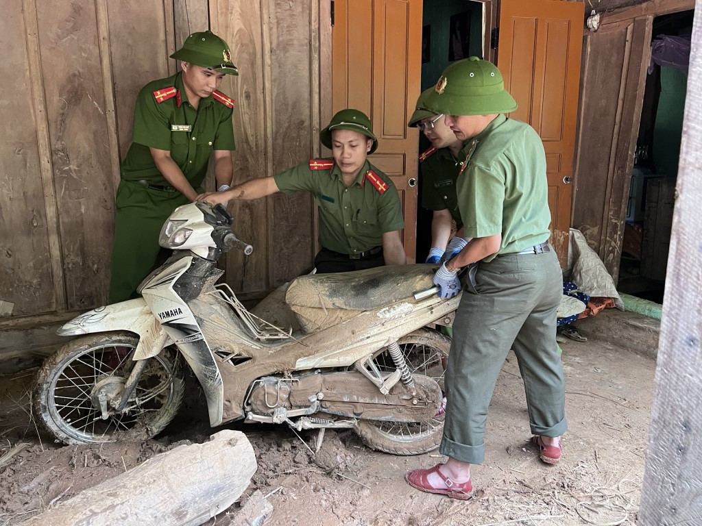 Phương tiện của người dân bị lớp bùn đất vùi lấp được lực lượng Công an đưa lên sắp xếp lại