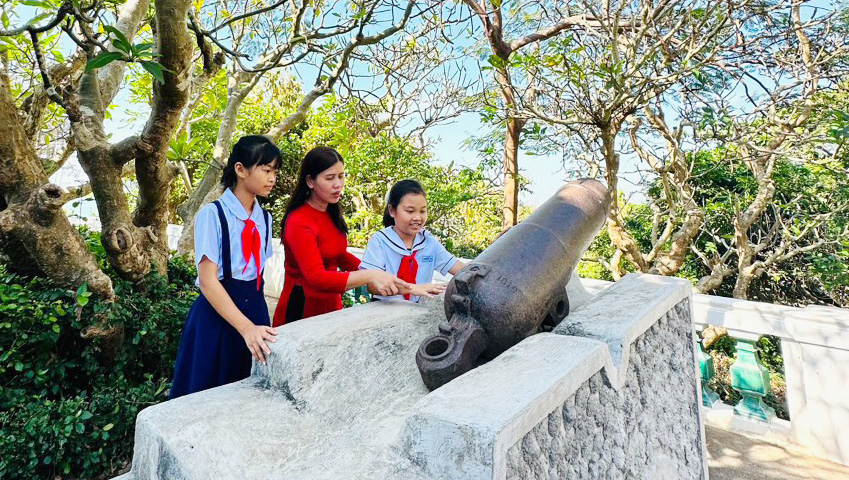 Cô và trò Trường Tiểu học Phước An tham quan khu trưng bày súng thần công trong khuôn viên di tích Bạch Dinh.