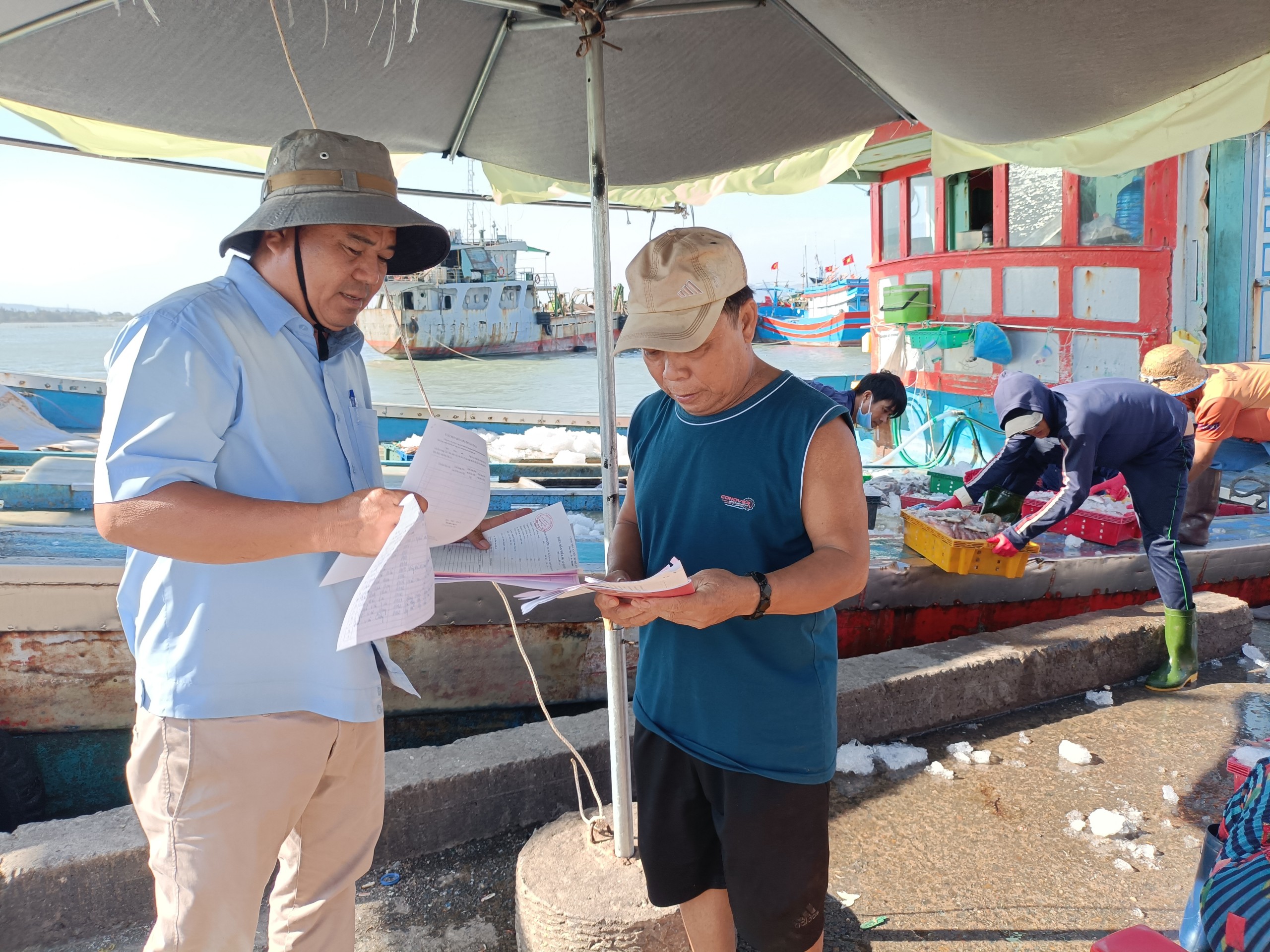 Nhân viên cảng cá Tân Phước (huyện Long Điền) kiểm tra giấy tờ, sản lượng và thu nhật ký khai thác tàu cá vừa cập bến  theo quy định IUU