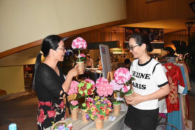 Chị Hoàng Ngân (trái) giới thiệu với khách hàng về sản phẩm bình hoa giấy do chị tự làm tại hội chợ tử tế.