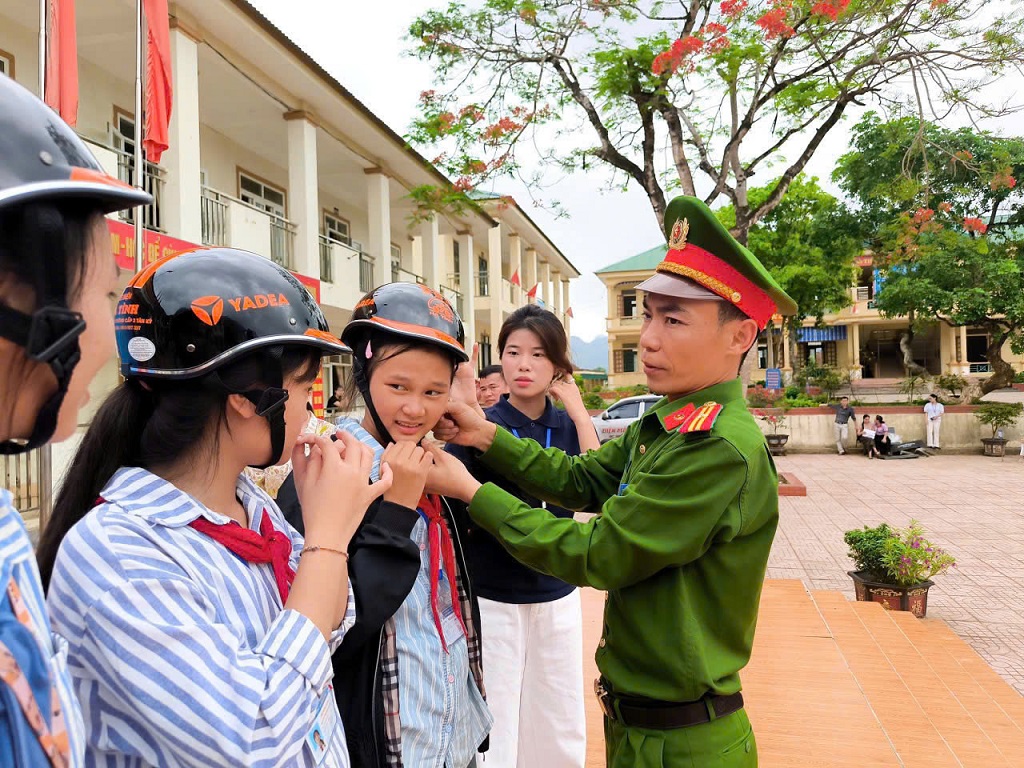 Công an xã Giai  Xuân hướng dẫn học sinh đội mũ bảo hiểm đúng cách