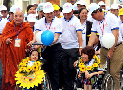 Chủ tịch nước Trương Tấn Sang (cầm trái bóng bay) sánh bước động viên trẻ khuyết tật.