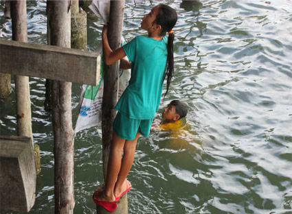 Cảnh các em nhỏ bất chấp nguy hiểm đu bám vào cọc trụ bằng gỗ dưới chân nhà hàng Thành Phát để lượm ve chai.