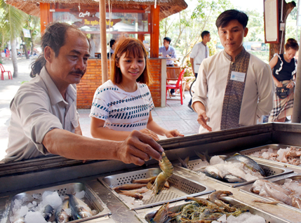 Bộ Quy tắc ứng xử văn minh du lịch, cùng các biện pháp chế tài sẽ giúp nâng cao ý thức, tính chuyên nghiệp cho người làm du lịch địa phương. Trong ảnh: Nhân viên Hương Phong-Hồ Cốc Beach Resort (bìa phải) hướng dẫn khách chọn mua hải sản.