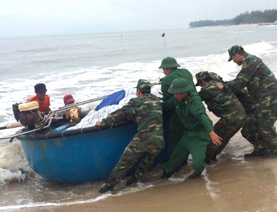 Chiến sĩ Đồn Biên phòng Phước Thuận giúp ngư dân kéo thuyền thúng lên bờ để tránh trú bão Tembin. 