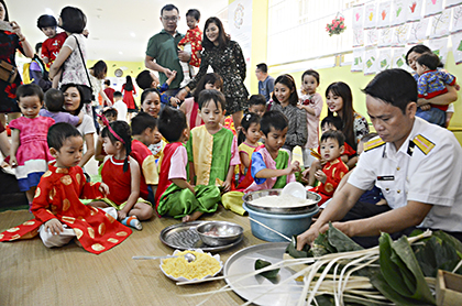 Học sinh Trường mầm non Thiên Minh (TP.Vũng Tàu) được cán bộ, chiến sĩ Trạm Ra đa 585 hướng dẫn gói bánh chưng. Ảnh: HẢI YẾN