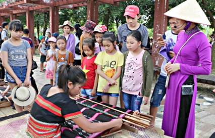 Trẻ em tìm hiểu nghề dệt thổ cẩm tại Làng Văn hóa - Du lịch các dân tộc Việt Nam.