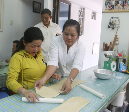 Cô Lê Thị Thanh Thiện (bìa phải) hướng dẫn người khuyết tật làm bánh bông lan trứng muối. 