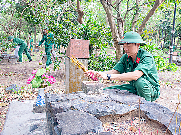 Cán bộ, chiến sỹ các lực lượng vũ trang huyện Côn Đảo thu dọn chân nhang trên phần mộ liệt sỹ.