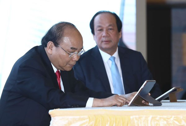 Thủ tướng Nguyễn Xuân Phúc và Bộ trưởng, Chủ nhiệm Văn phòng Chính phủ Mai Tiến Dũng ký sổ văn bản điện tử. 