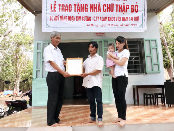 Ông Nguyễn Tám (bìa trái), Phó Chủ tịch UBND  xã Xà Bang trao quyết định bàn giao nhà cho gia đình anh Nguyễn Phương Bình. 