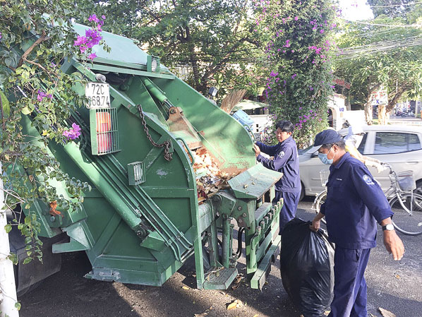 Công nhân Công ty CP dịch vụ môi trường và công trình đô thị Vũng Tàu đưa rác lên xe chuyên dùng.