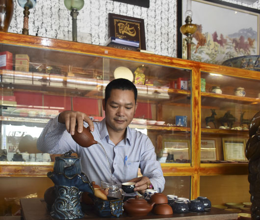 Anh Lê Văn Kiên, chủ Cổ Trà Quán bên các cổ vật sưu tầm được trưng bày tại quán.