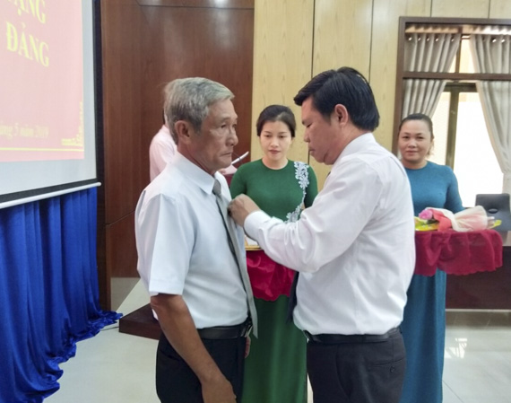 Đồng chí Nguyễn Văn Xinh, Trưởng ban Tuyên giáo Tỉnh ủy trao Huy hiệu 40 năm tuổi Đảng cho đảng viên Phạm Văn Hào. 