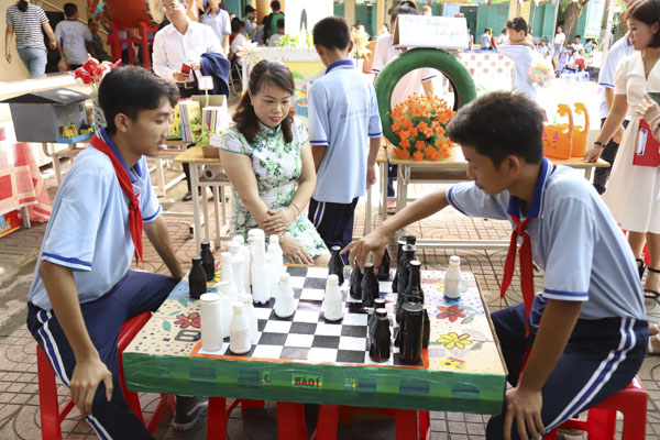 Em Nguyễn Mạnh Tính (bên trái) và bạn cùng lớp chơi cờ vua trên sản phẩm do chính các em thực hiện.