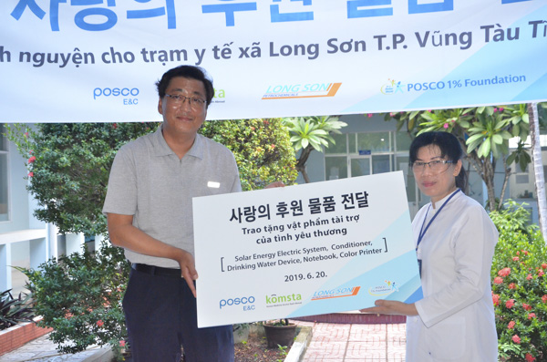 Ông Lee Sang Yeop, đại diện Công ty Posco E&C trao quà cho đại diện Trạm Y tế xã Long Sơn.