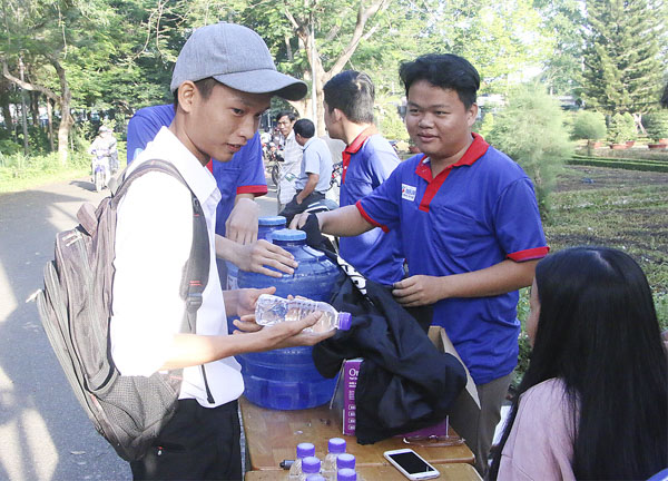 Tình nguyện viên tiếp sức mùa thi ở điểm thi THPT Ngô Quyền (huyện Châu Đức) hỗ trợ nước uống cho TS tham gia thi. Ảnh: TƯỜNG NGÂN