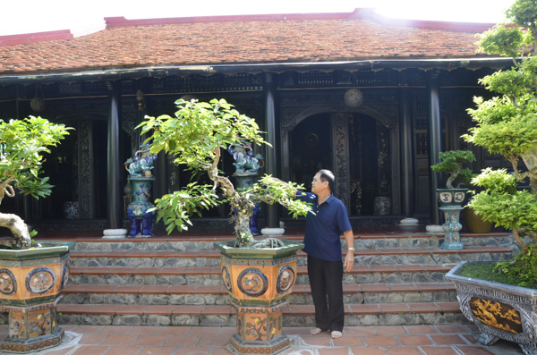 Ông Trần Đức Hoan chăm sóc cây cảnh trước sân ngôi nhà cổ.