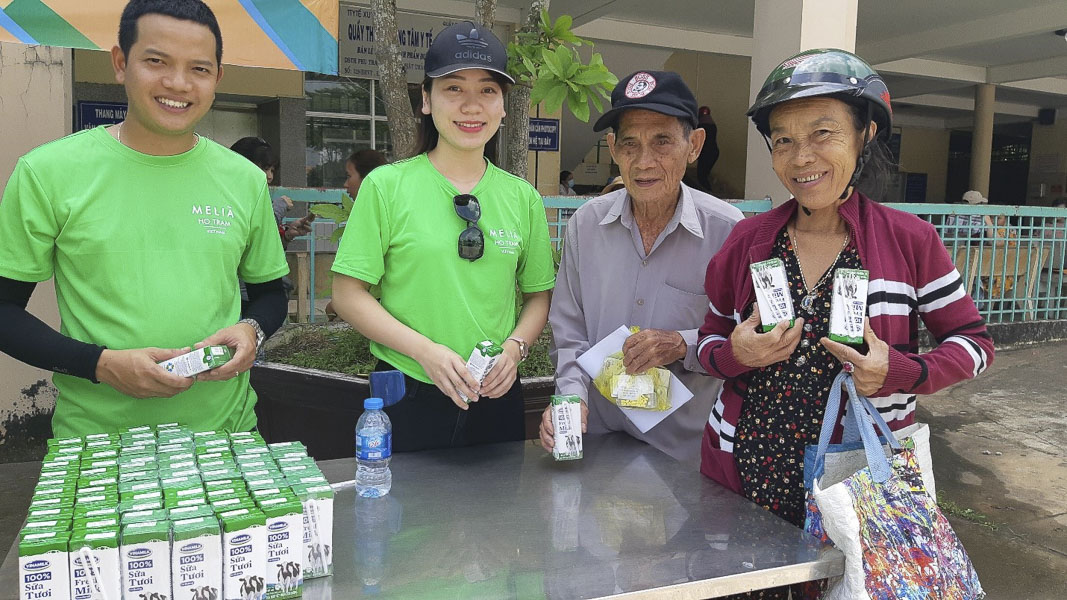 Người thân và bênh nhân (bìa phải) tại TTYT huyện Xuyên Mộc rất vui khi được nhận quà và suất cơm trưa do Melia Hồ Tràm nhận quà hỗ trợ.