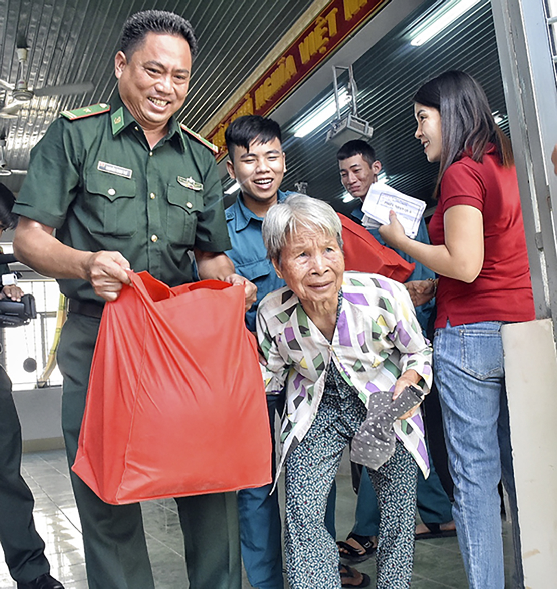 Lực lượng Biên phòng mang quà và đưa người già ra xe của người thân chở về nhà.