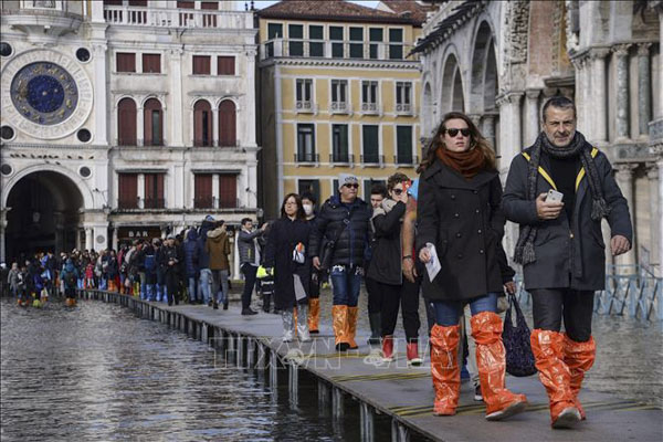 Người dân phải đi bằng cầu tạm qua con phố bị ngập do đợt thủy triều dâng cao nhất trong 50 năm qua ở Venice ngày 14/11/2019. (Nguồn: AFP)