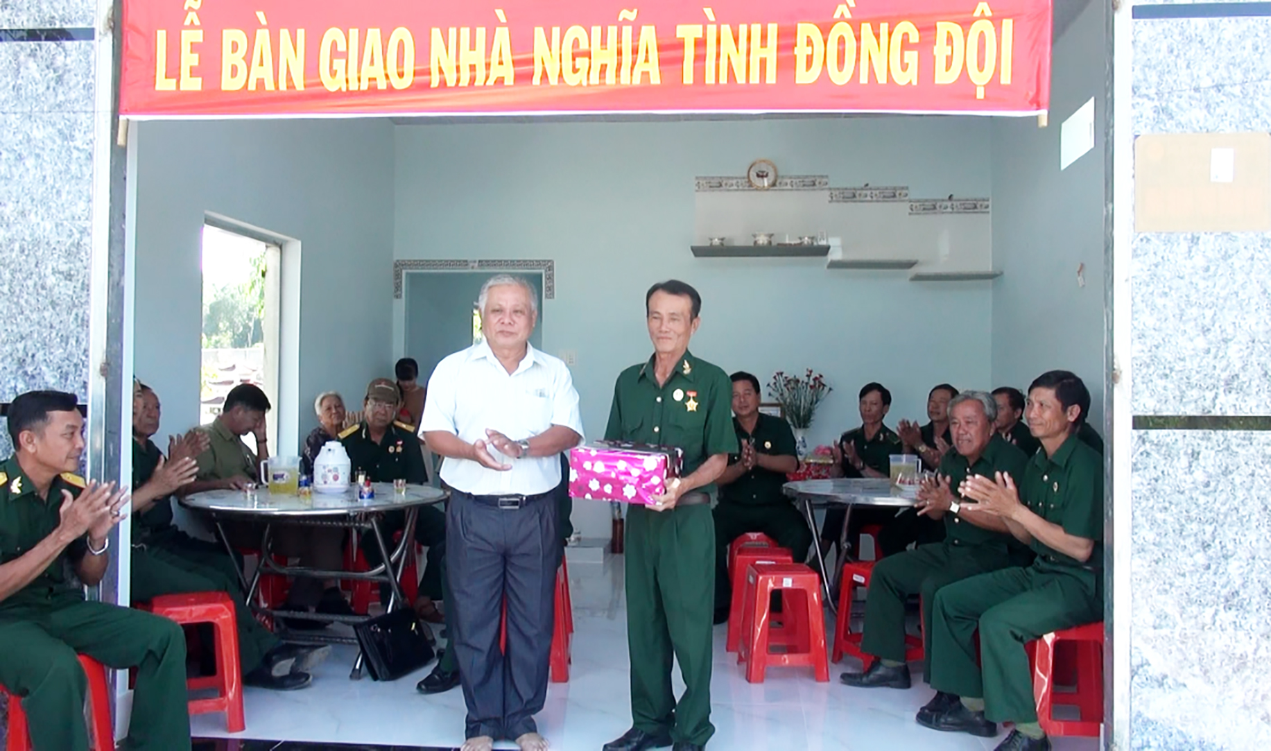 Ông Nguyễn Văn Quằn (bên trái), Bí thư Đảng ủy xã An Ngãi tặng quà cho CCB Đặng Văn Phước tại lễ bàn giao nhà “Nghĩa tình đồng đội”.