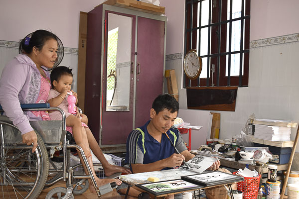 Anh Nguyễn Minh Thắng hoàn thiện bức tranh đồng quê bằng màu acrylic bên cạnh vợ  và con trong ngôi nhà hạnh phúc mới xây.