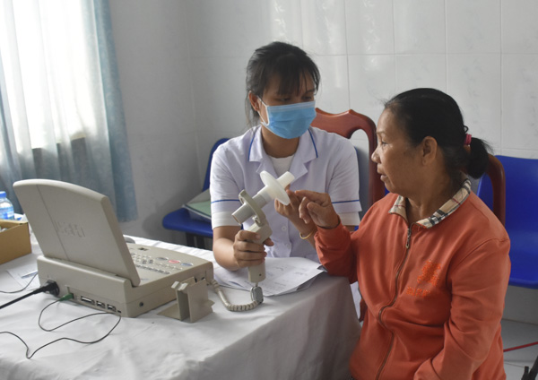 Người bệnh COPD đến khám định kỳ sẽ được bác sĩ chỉ định làm xét nghiệm máu, chụp X-Quang tim phổi, siêu âm và đo chức năng hô hấp để nhận định được mức độ tắc nghẽn và giai đoạn của bệnh. Trong ảnh: Nhân viên y tế của Bệnh viện Phổi Phạm Hữu Chí hướng dẫn bệnh nhân sử dụng dụng cụ đo chức năng hô hấp để tầm soát bệnh hen, COPD.