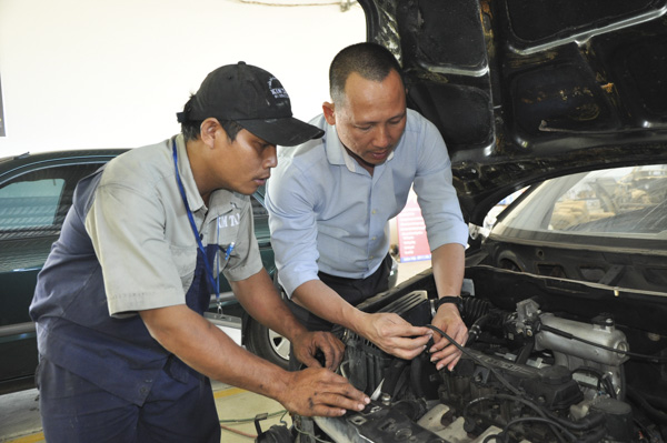 Thầy Nguyễn Kim Tâm (bên phải) hướng dẫn học trò sửa chữa động cơ ô tô tại Salon ô tô Kim Tâm.