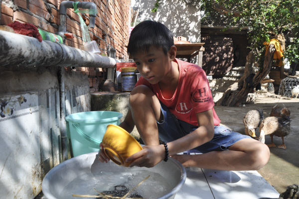 Sau giờ học, em Nguyễn Thành Danh phụ giúp bà nội làm các công việc lặt vặt trong nhà.