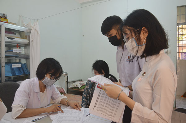 Cô Phạm Thị Nga, nhân viên y tế Trường THPT Vũng Tàu hướng dẫn HS điền vào phiếu thông tin du lịch của bản thân và gia đình trong thời gian nghỉ học.