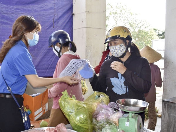 Tình nguyện viên Bà Rịa Youth (trái) phát khẩu trang và tờ rơi tuyên truyền phòng chống dịch COVID-19 cho người dân tại chợ Kim Hải (phường Kim Dinh, TP. Bà Rịa).