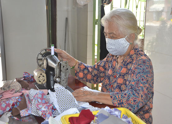 Cụ Nguyễn Thị Trang, 80 tuổi, cần mẫn may khẩu trang tặng người nghèo. Mỗi ngày cụ may được 70 chiếc và đặt trước nhà để mọi người đi qua nhận về.    Ảnh: CẨM NHUNG