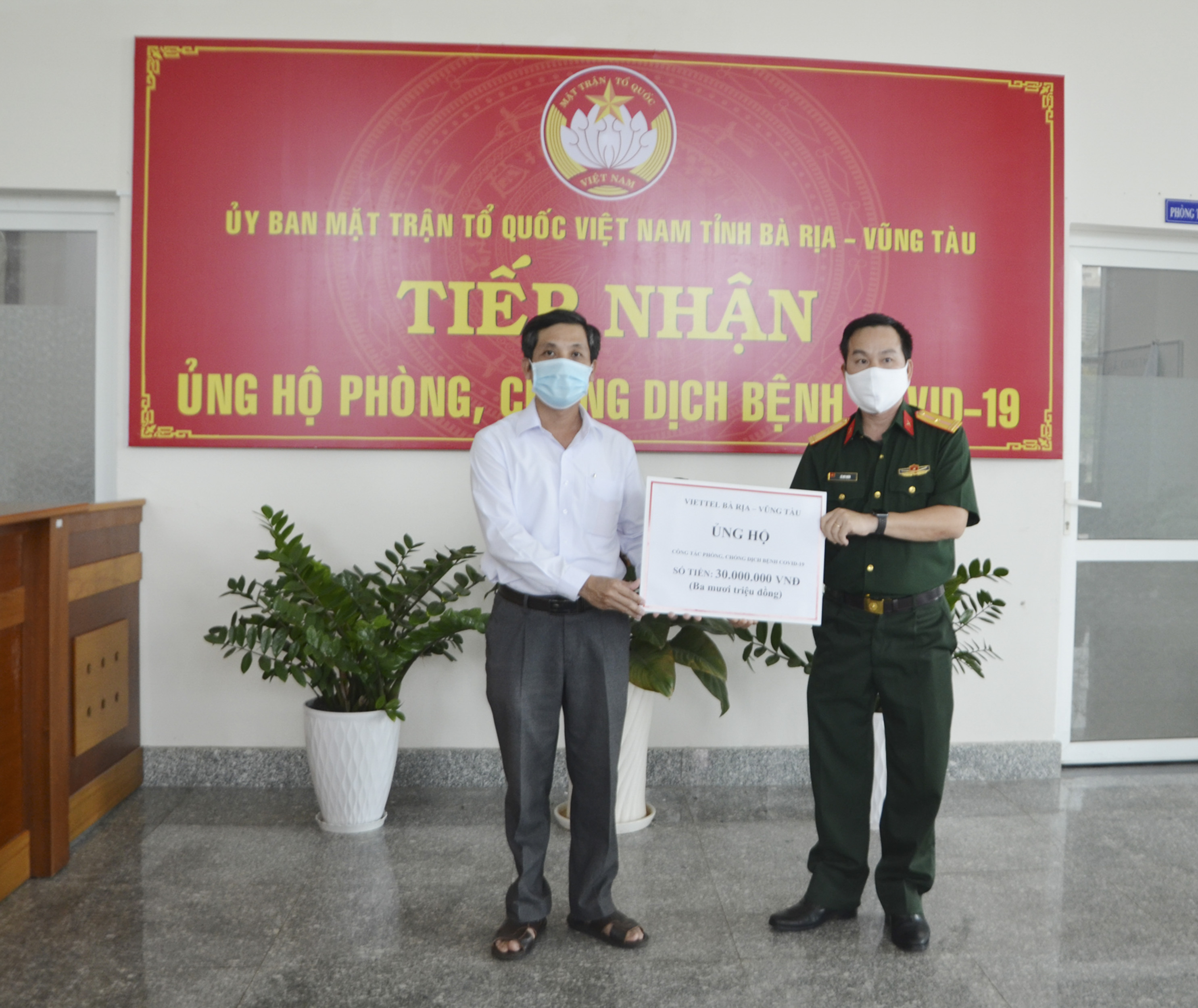 Thiếu tá Lê Huy Huân, Phó Giám đốc Viettel BR-VT (bìa phải) trao bảng tượng trưng số tiền 30 triệu đồng ủng hộ phòng chống dịch bệnh COVID-19 cho đại diện UBMTTQVN tỉnh chiều 13/4.