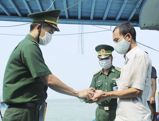 Cán bộ, chiến sĩ Đồn Biên phòng Bến Đá yêu cầu thuyền viên chấp hành việc rửa tay sát khuẩn trước khi làm thủ tục xuất, nhập cảnh.