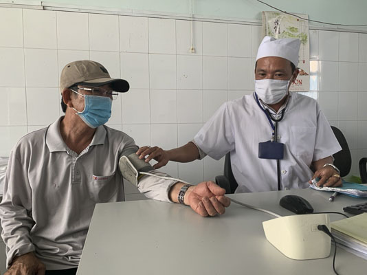 Y sĩ Nguyễn Tiến Khoa đo huyết áp cho ông Võ Văn Le.
